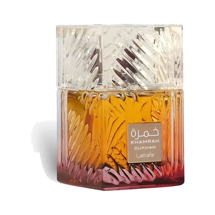 Frasco cuadrado de vidrio tallado con degradado de ámbar a rosa vino, tapa maciza facetada tipo cristal y placa dorada en el frente, sobre fondo blanco.