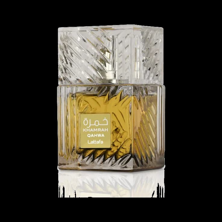 Frasco cuadrado de vidrio tallado con líquido dorado, tapa maciza facetada transparente y etiqueta crema con letras doradas, sobre fondo blanco.