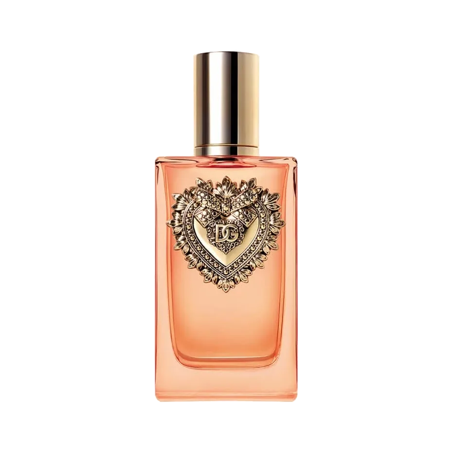 Frasco rectangular de vidrio coral con tapa cilíndrica dorada y un corazón sagrado de metal dorado en relieve sobre la cara frontal, sobre fondo blanco.